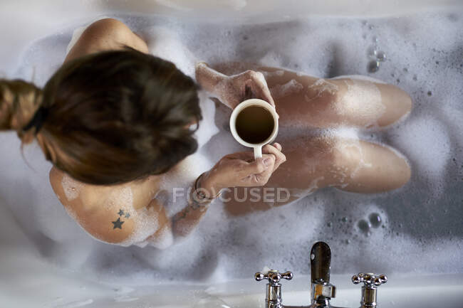 Woman having a relaxing bath and a cup of coffee in the bathtub — Stock Photo