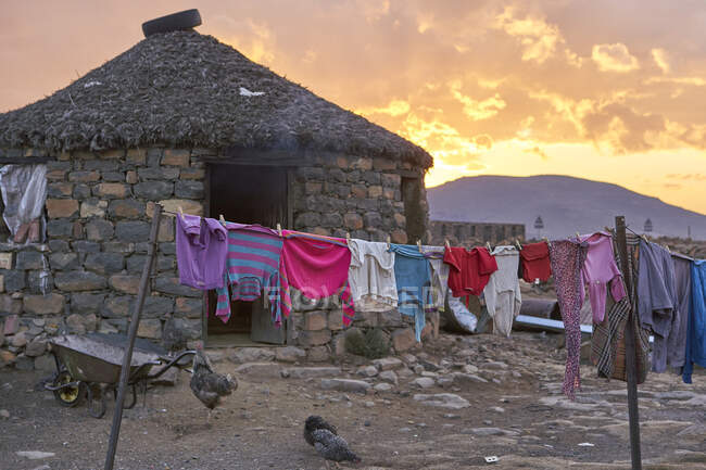Pôr do sol em uma casa típica com roupas penduradas, Lesoto, África — Fotografia de Stock