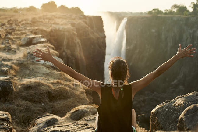 Femme avec les bras ouverts profitant de la vue sur Victoria Falls, Zimbabwe — Photo de stock