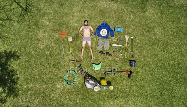 Blick von oben auf einen Gärtner im Liegen auf dem Rasen mit allen Werkzeugen, die er für die Pflege des Gartens braucht — Stockfoto