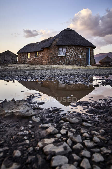 Casas de pedra tradicionais e reflexão em uma poça, Lesoto — Fotografia de Stock