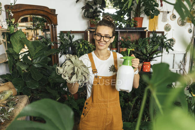 Smiling young woman caring for plants in a small shop — Stock Photo