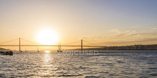 25 апреля Мост через реку Тагус против неба на закате в Лиссабоне, Португалия — стоковое фото