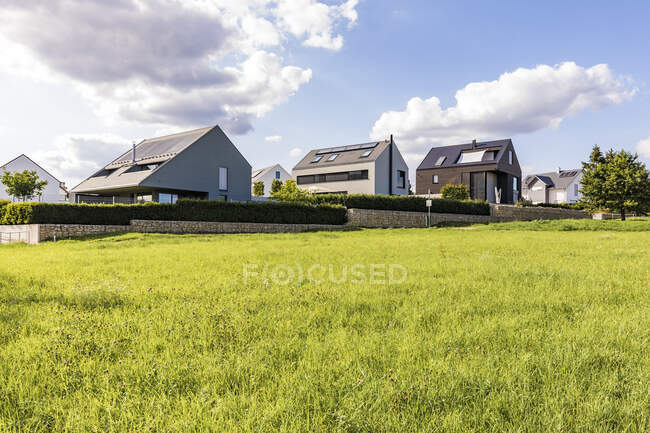 Casas con paneles solares en el techo por campo contra el cielo, Baden-Wrttemberg, Alemania - foto de stock