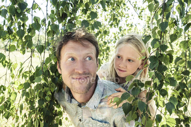 Vater trägt Tochter huckepack unter Birke — Stockfoto