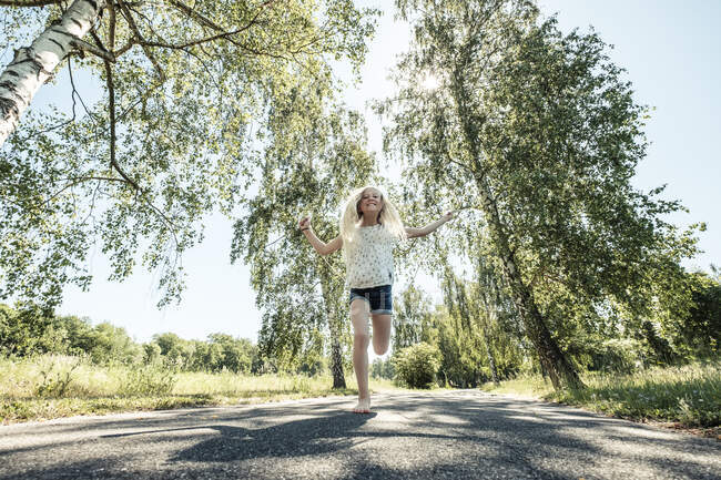 Happy girl skipping rope on a park path — Stock Photo