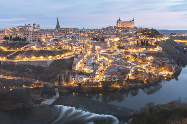 Spanien, Provinz Toledo, Toledo, Tejo und beleuchtete Stadt im Morgengrauen — Stockfoto