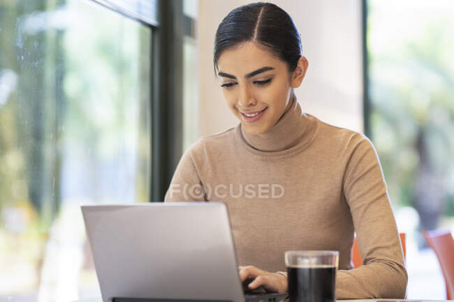 Усмішка молода жінка використовує ноутбук у кафе. — стокове фото