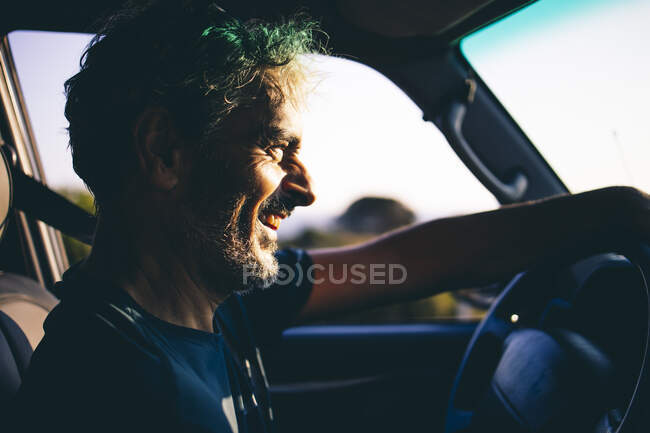 Mature man driving at sunset — Stock Photo