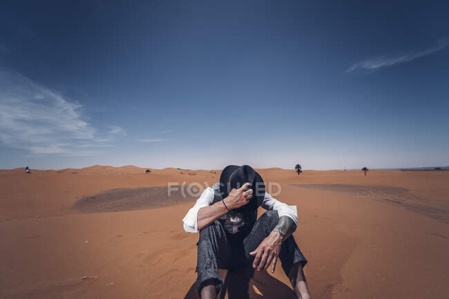 Man putting on his hat in the dunes of the desert of Morocco — Stock Photo