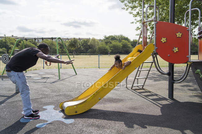 Padre con figlia scorrevole su un parco giochi — Foto stock