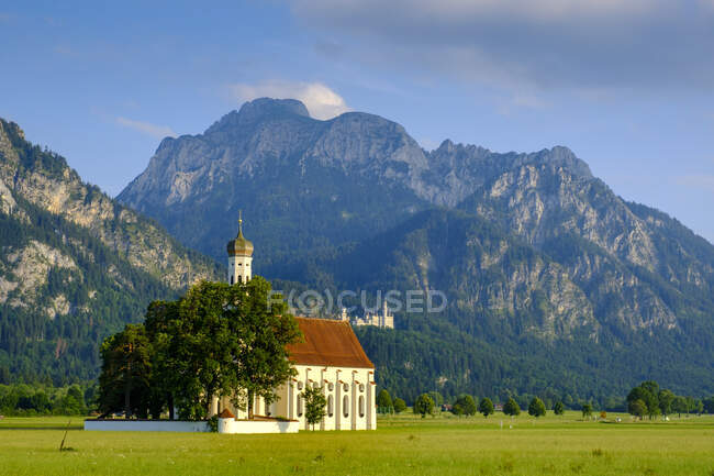 Chiesa di San Colomano su terreni erbosi contro le montagne a Schwangau, Germania — Foto stock