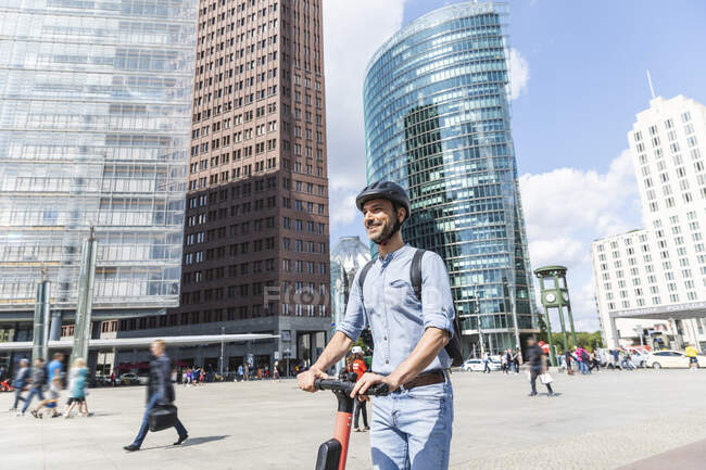 Homme d'affaires avec e-scooter sur la place de la ville, Berlin, Allemagne — Photo de stock