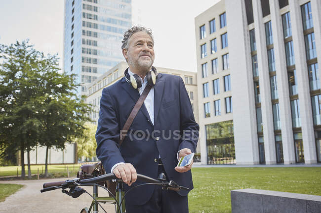 Reifer Geschäftsmann mit Fahrrad in der Stadt — Stockfoto
