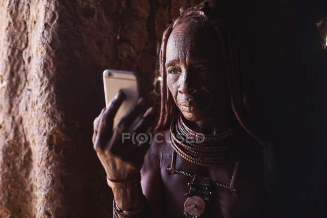 Old Himba femme vérifier son smartphone, Oncocua, Angola — Photo de stock