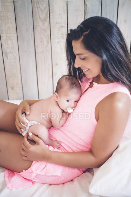 Felice madre seduta sul letto con il bambino — Foto stock