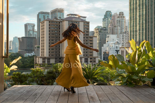 Vista posteriore della donna che balla sulla terrazza sul tetto, Bangkok, Thailandia — Foto stock