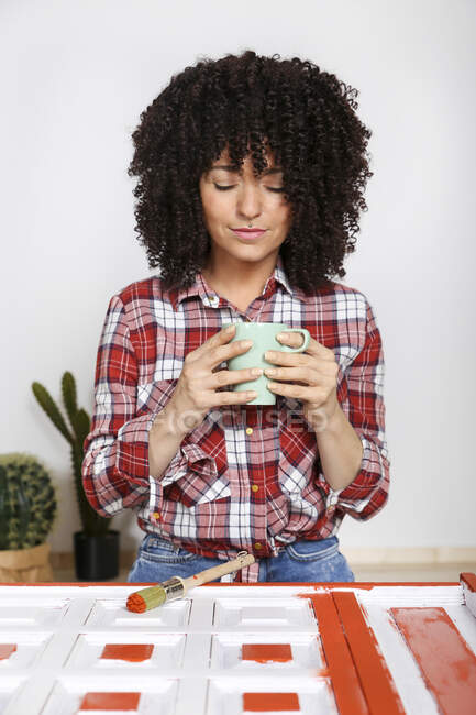 Donna che tiene una tazza di caffè a casa, mobili dipinti — Foto stock