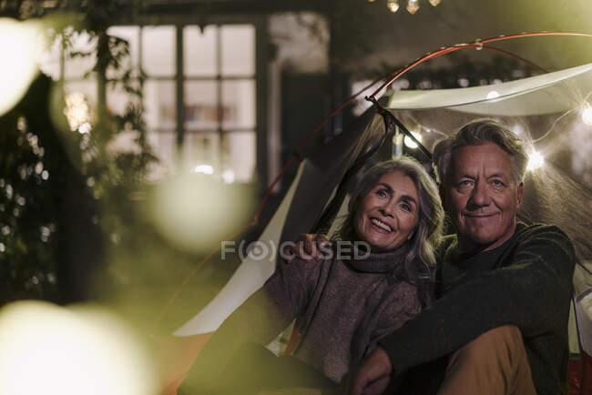 Feliz pareja de ancianos acampando en el jardín de su casa por la noche - foto de stock