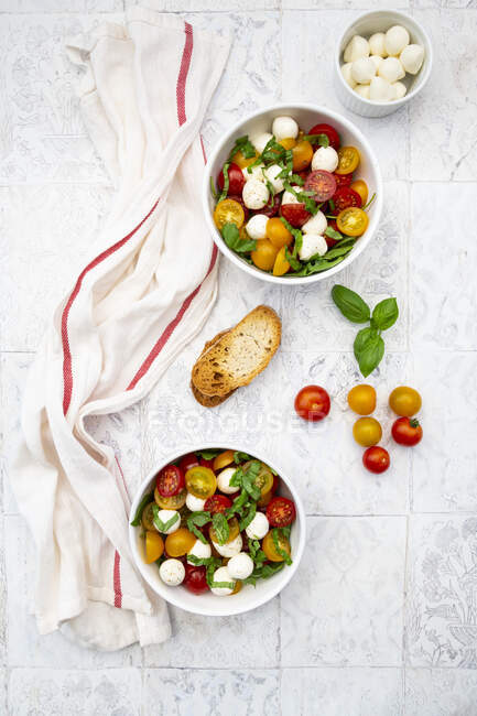 Серветка, скибочки хліба і дві миски свіжого салату лежать на плитковому столі — стокове фото