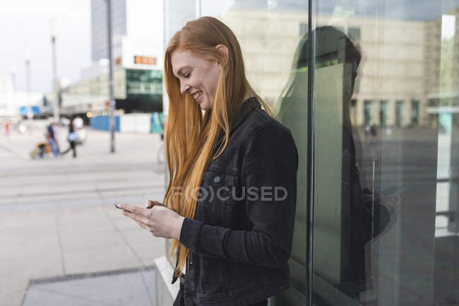 Redheaded young woman text messaging, Berlim, Alemanha — Fotografia de Stock