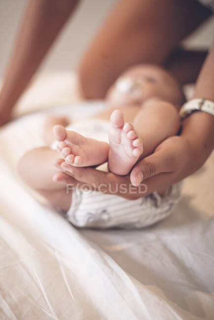 Mother's hand holding tiny feet of baby boy, close-up — Stock Photo
