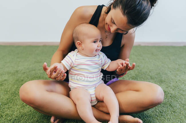 Молода мати з дитиною під час тренувань у гімнастиці. — стокове фото