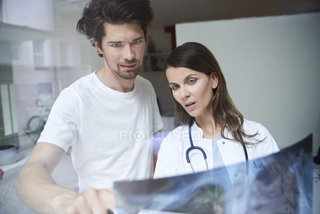Dos doctores con imagen de rayos X detrás del cristal de la ventana — Stock Photo