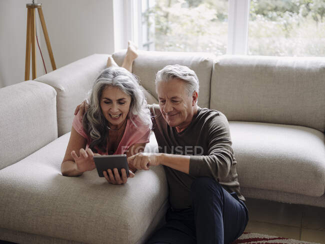Felice coppia anziana relax sul divano a casa utilizzando tablet — Foto stock