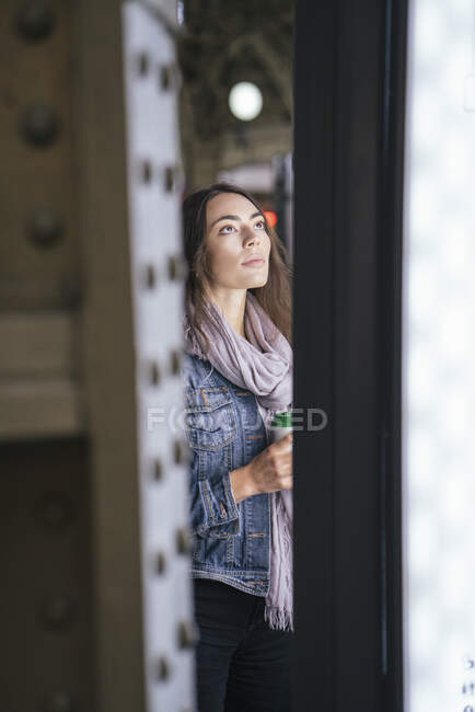 Young female traveller with coffee to got looking on destination board on the train station — Stock Photo