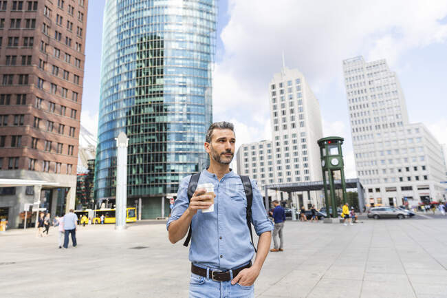Hombre en la ciudad sosteniendo una taza de café, Berlín, Alemania - foto de stock