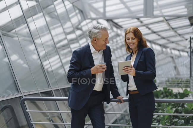 Uomo d'affari e donna d'affari sorridenti che parlano in un moderno edificio per uffici — Foto stock