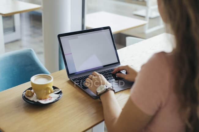 Étudiante tapant sur son ordinateur au café — Photo de stock