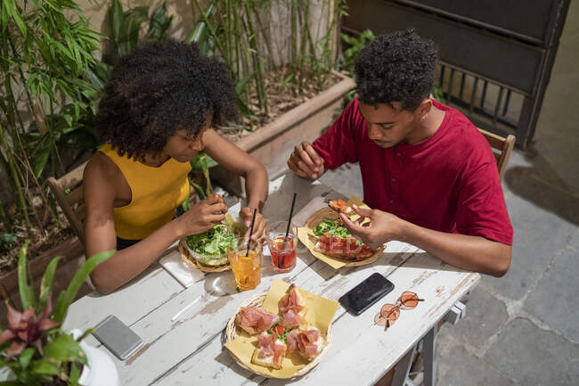 Young couple having a drink and amtipasti at an outdoor bar — Stock Photo