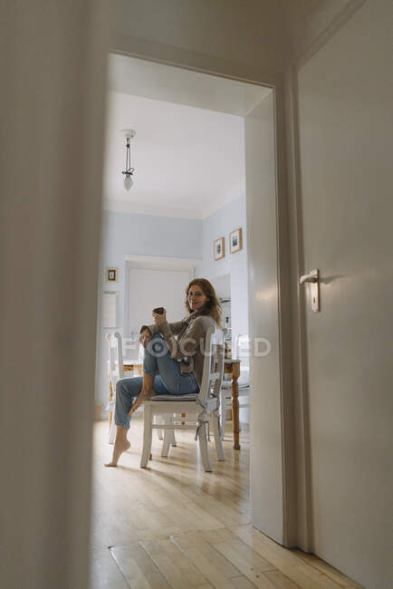 Donna matura seduta in cucina, che beve caffè — Foto stock