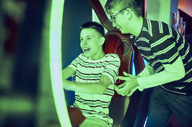 Amigos adolescentes jugando y divirtiéndose con un simulador de conducción en un arcade de diversiones - foto de stock