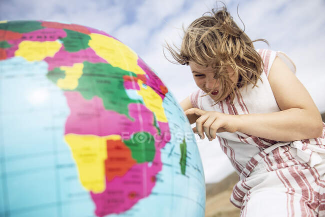 Little girl pointing on inflatable globe — Stock Photo