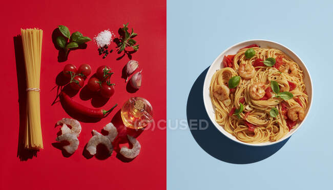 Directly above shot of shrimp pasta by ingredients on colored background — Stock Photo