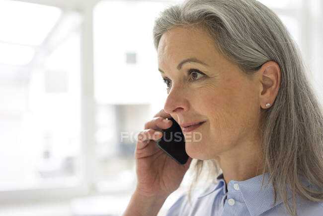 Portrait of mature businesswoman on the phone in office — Stock Photo
