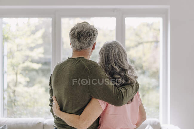 Погляд на старшу пару, яка дивиться у вікно будинку. — стокове фото