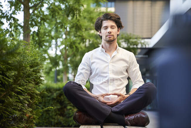 Businessman doing yoga on a bench in the city — Stock Photo
