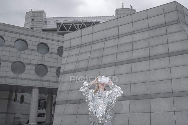 Ragazza in abito argentato. guardando attraverso gli occhiali VR nella città futuristica — Foto stock