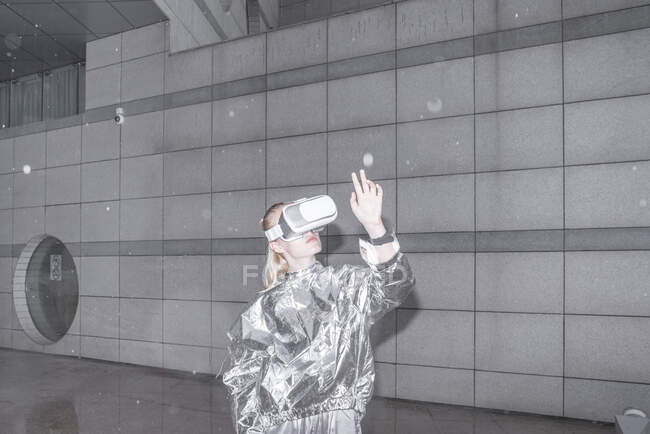Ragazza in abito d'argento guardando attraverso VR occhiali, guardando la sua mano — Foto stock