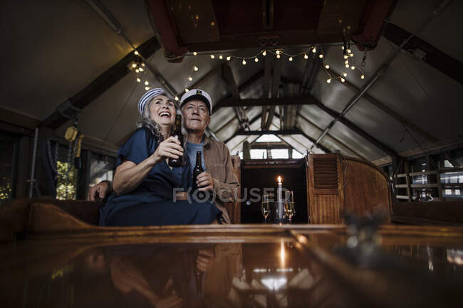 Счастливая старшая пара выпивает на лодке в лодочном сарае — стоковое фото