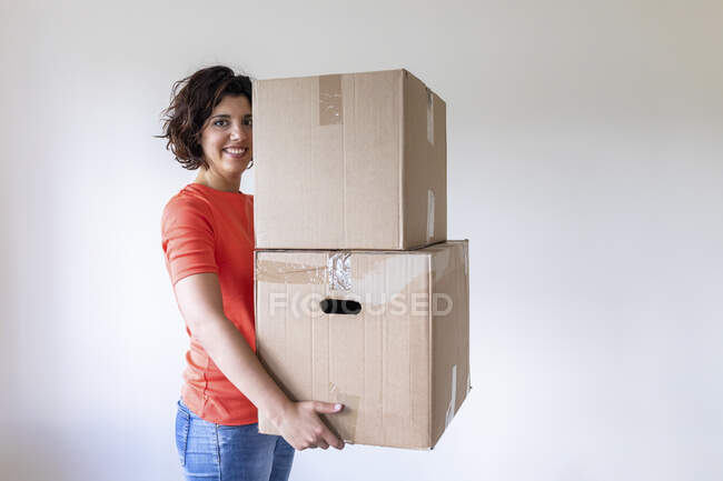 Donna che si trasferisce in una nuova casa portando scatole di cartone — Foto stock