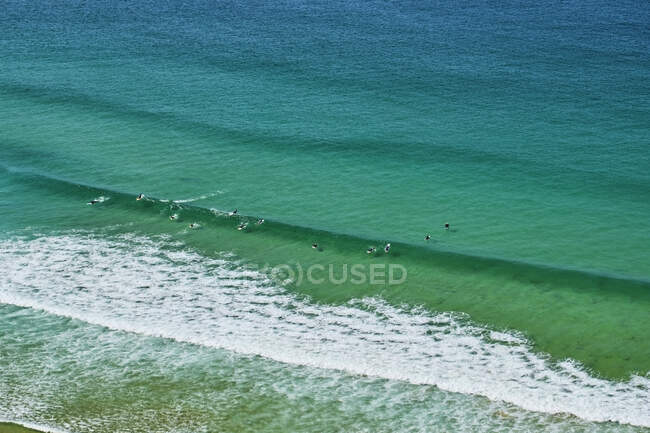 Portugal, Algarve, Arrifana, Gente surfeando en aguas costeras verdes - foto de stock