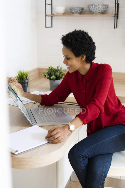 Mujer joven sonriente usando el ordenador portátil en casa - foto de stock
