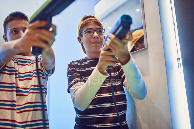 Amici adolescenti che sparano con le pistole in una sala giochi di divertimento — Foto stock