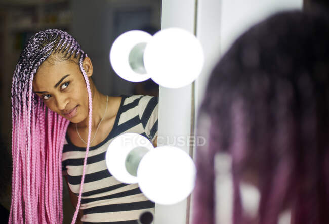 Задоволена молода жінка з рожевими плечима, дивлячись на своє дзеркальне зображення. — стокове фото