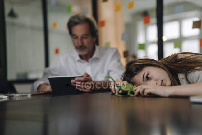 Anziano buisinessman utilizzando tablet e ragazza giocare con camaleonte figurina in ufficio — Foto stock